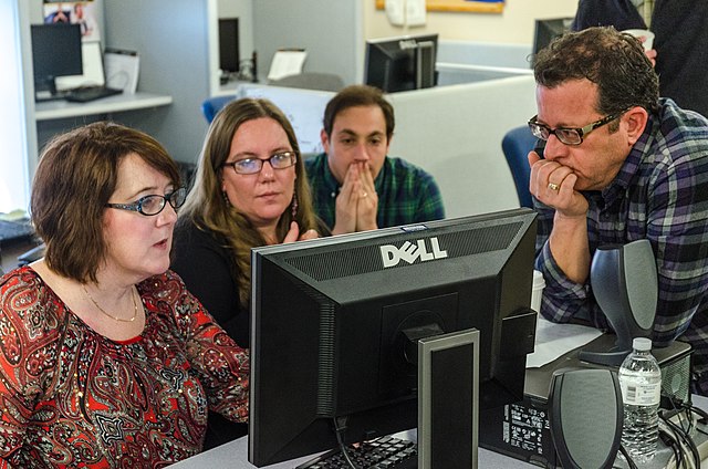 Picture of 4 people (2 male 2 female) around a computer